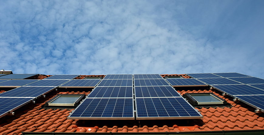 Solar panels on red tiled roof against blue sky