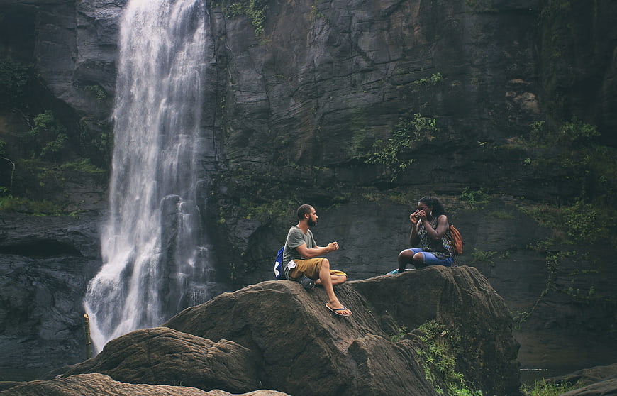 Couple relaxing on rocks by a scenic waterfall in nature