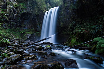 Misty Waterfall Cascading Through Mossy Forest Rocks