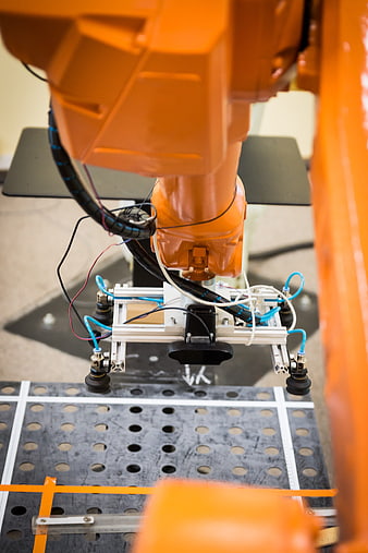 Close-up of orange industrial robotic arm with pneumatic gripper