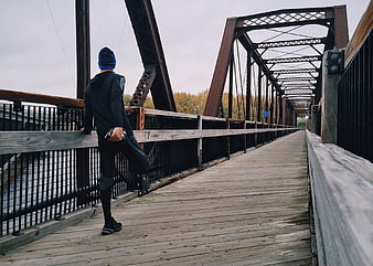 Man stretching on wooden bridge railing