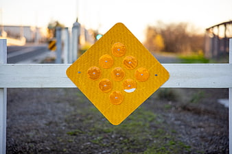 Yellow Diamond Reflective Road Sign on White Fence