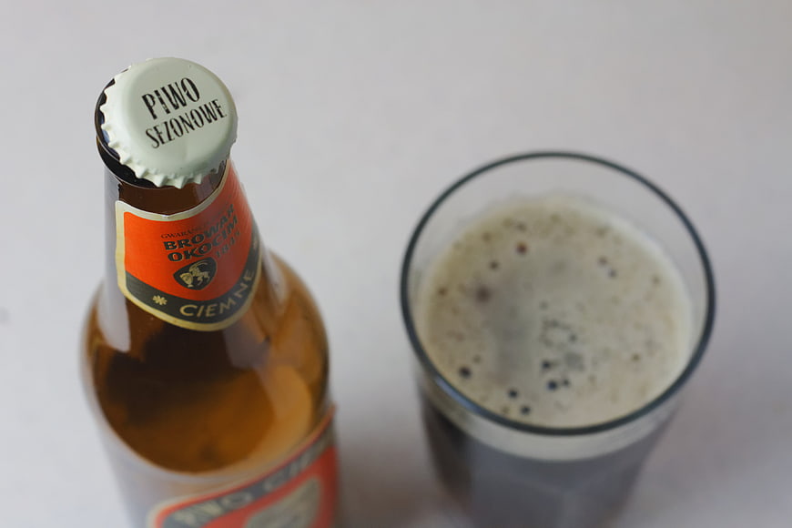 Top View of Okocim Beer Bottle and Glass on White Background