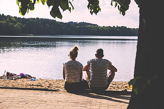 Couple sitting by the lake enjoying a sunny summer day