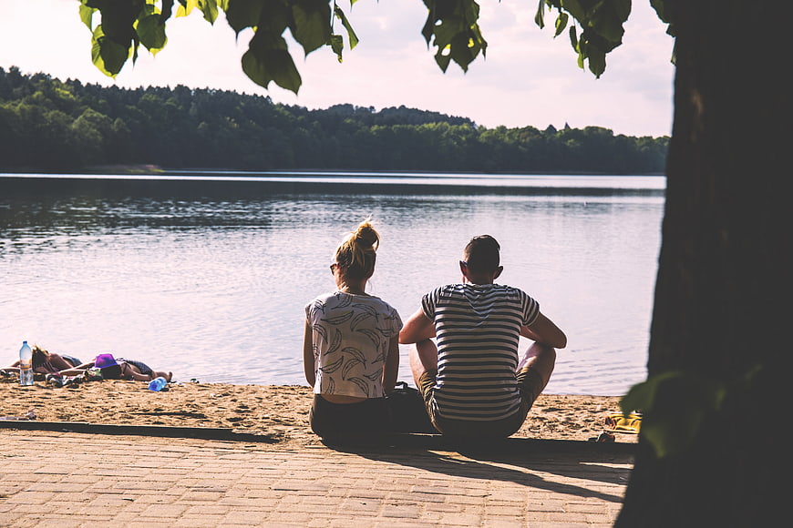 Couple sitting by the lake enjoying a sunny summer day