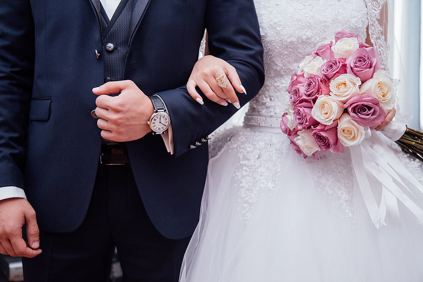 Wedding couple holding hands with pink rose bouquet