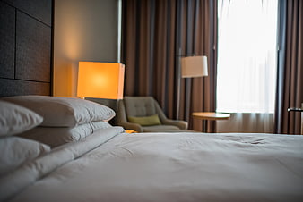 Cozy Hotel Bedroom Interior With White Linens And Warm Lamp Light