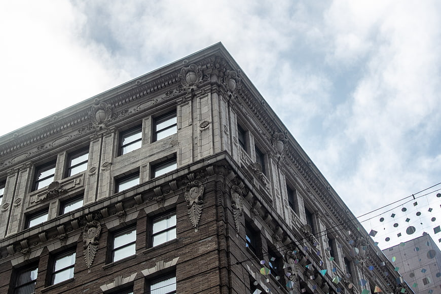 Low angle view of ornate historic building corner against cloudy sky