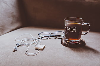Coffee mug, glasses, and earphones on a beige couch