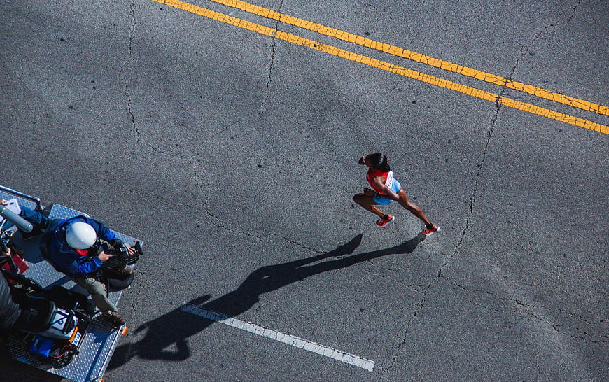 Aerial view of female marathon runner on asphalt road
