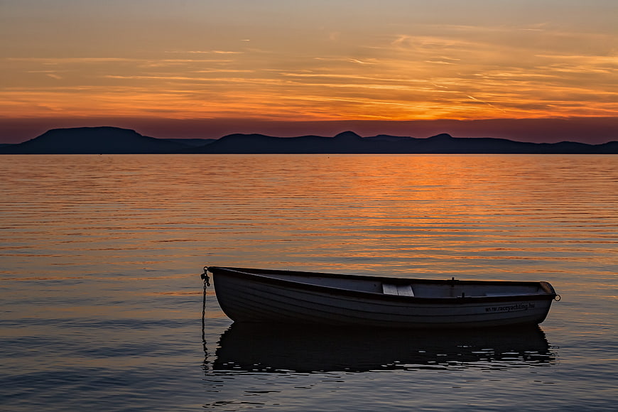 Solitary Rowboat on Calm Lake at Golden Sunset