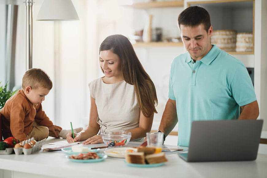Happy family having breakfast and working on laptop at home