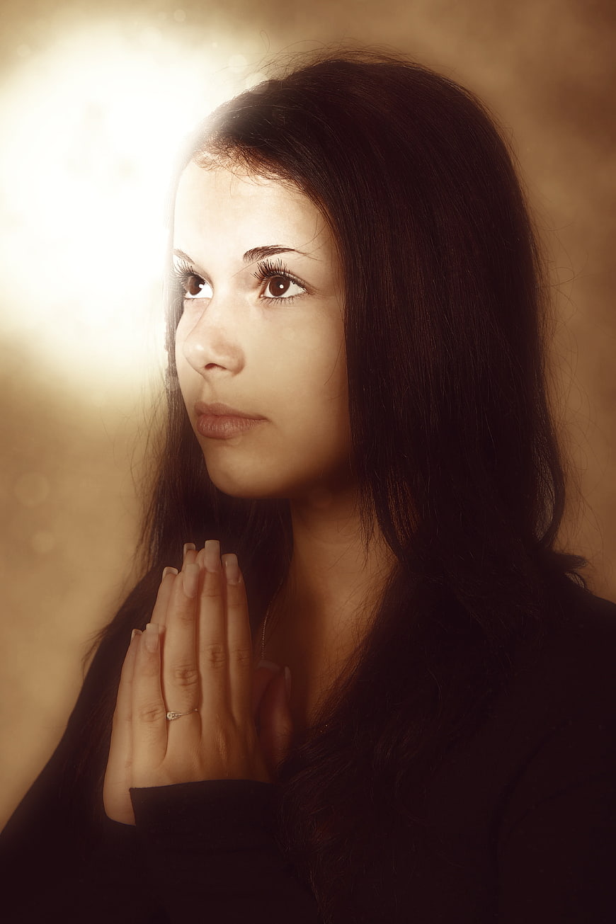 Woman in Prayer with Hands Folded in Warm Light