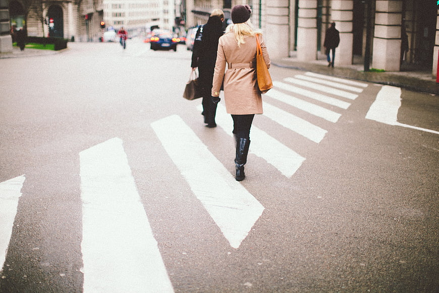 Two women walking away on city crosswalk