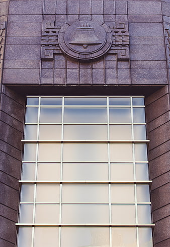 Art Deco Building Facade with Bell Emblem and Grid Window