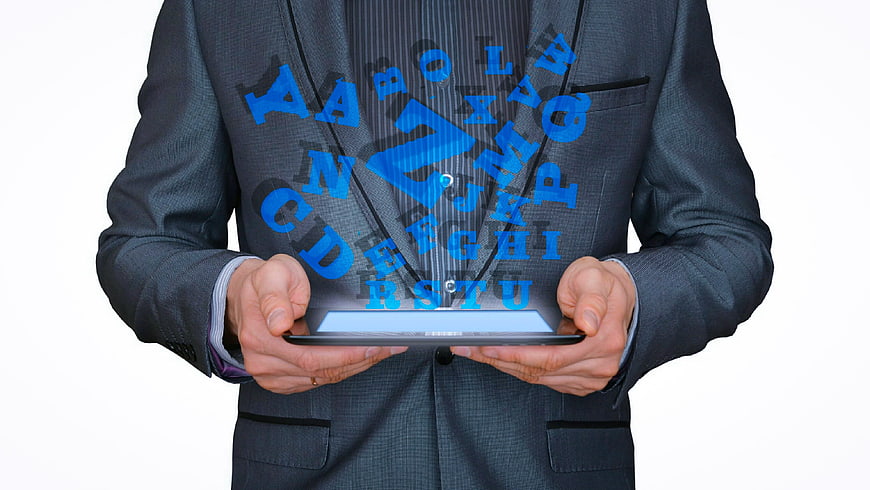 Businessman holding tablet with floating blue alphabet letters