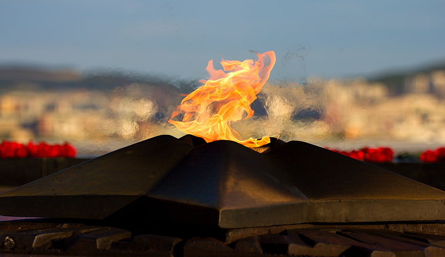 Close-up of a gas stove burner flame with blurred city background