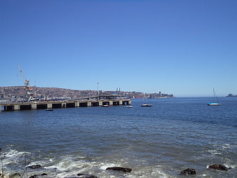 Coastal harbor view with pier, boats, and city skyline