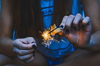 Close-up of hands holding a lit sparkler at night