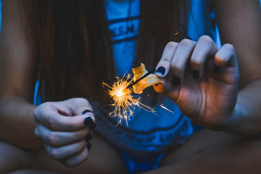 Close-up of hands holding a lit sparkler at night