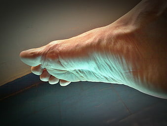 Close-up of a human foot arch and toes on a tiled floor