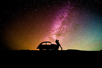 Silhouette of couple and car under vibrant Milky Way night sky