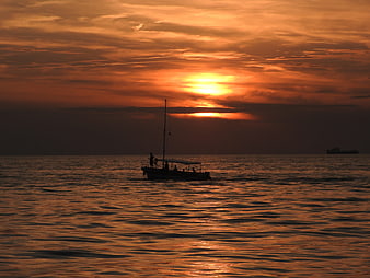 Silhouette of boat on ocean during golden sunset