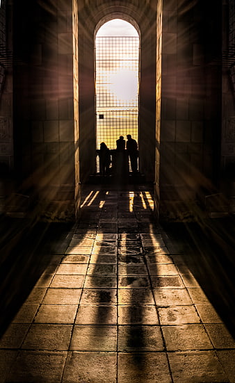 Silhouetted figures in arched doorway with dramatic sunbeams