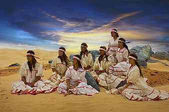 Group of Indigenous Women in Traditional Dress Seated in Desert Landscape
