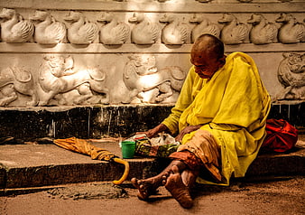 Elderly man in yellow robe sitting on temple steps