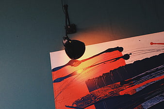Abstract painting illuminated by spotlight on blue wall