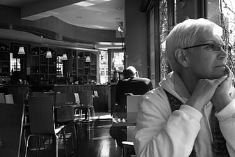 Senior woman looking out cafe window in black and white