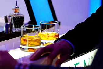 Whiskey Glasses on Bar Counter with Bartender Hand