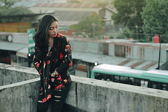 Pensive Woman in Floral Jacket on Urban Rooftop
