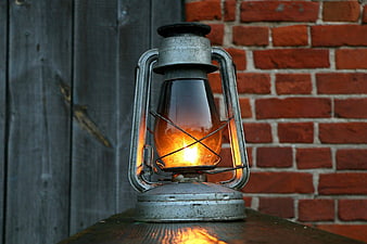 Vintage Oil Lantern Glowing Against Brick and Wood