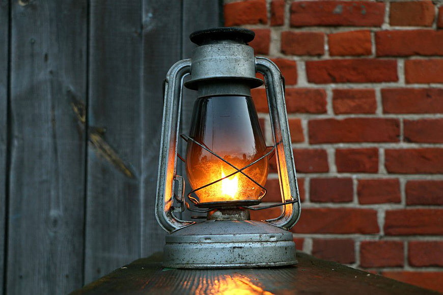 Vintage Oil Lantern Glowing Against Brick and Wood