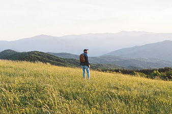 Man Hiking in Grassy Mountain Field with Backpack