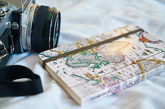 Vintage Camera and Map Notebook on White Bedding