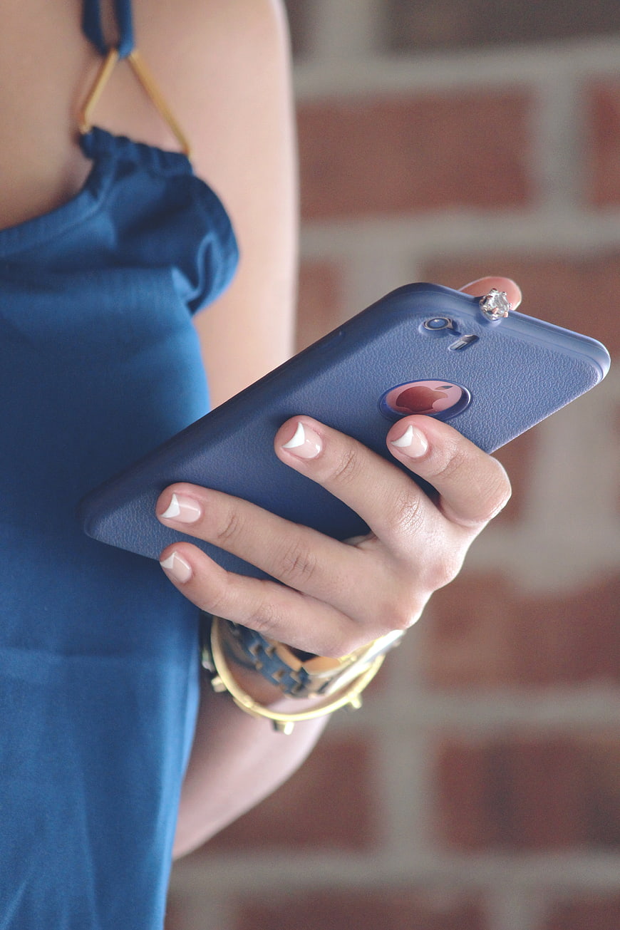 Woman holding blue smartphone with French manicure
