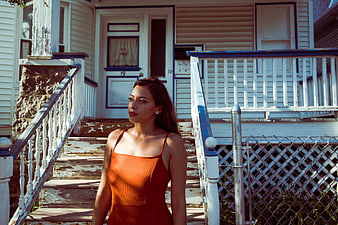 Woman in Orange Dress Standing on Weathered Porch Steps
