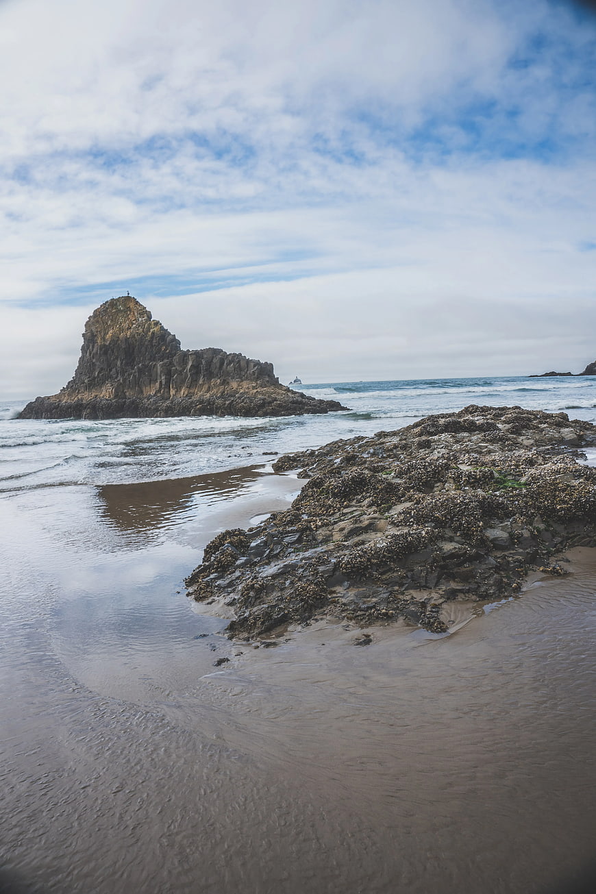 Dramatic Rocky Sea Stack on Sandy Beach with Ocean Waves