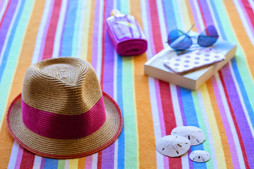 Summer vacation essentials on colorful striped beach towel