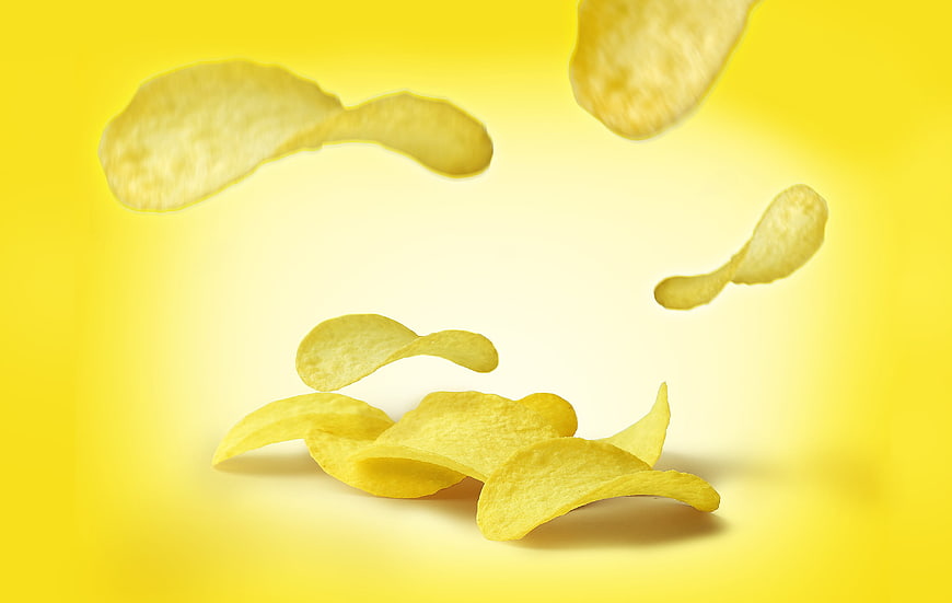 Flying potato chips on yellow background