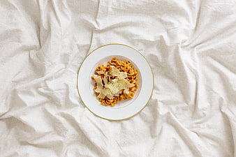 Top view of pasta dish on white bed sheet background