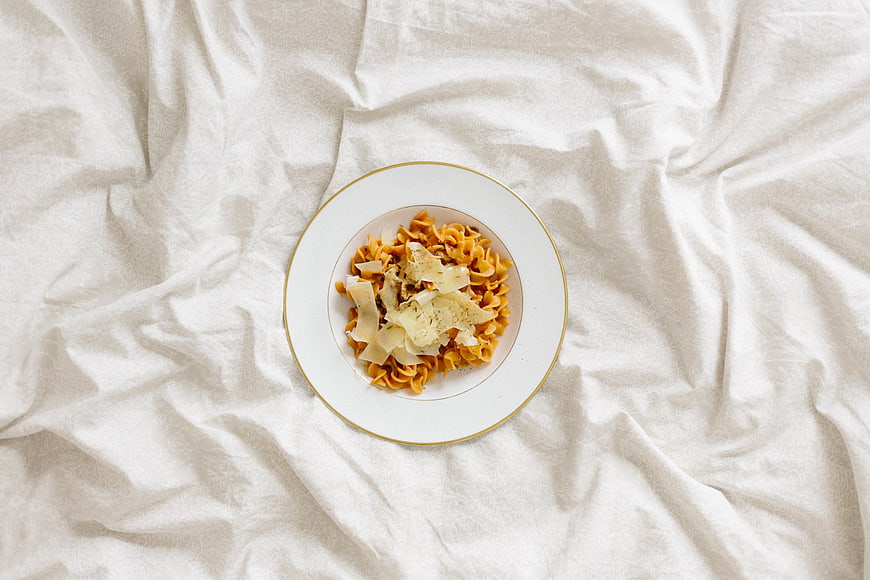 Top view of pasta dish on white bed sheet background
