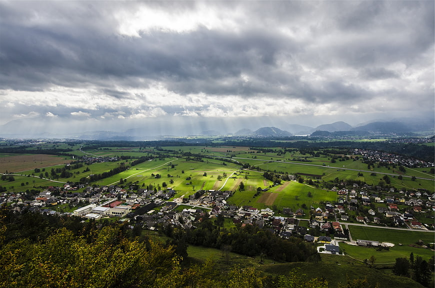 Dramatic sunbeams over green valley landscape with village