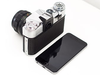 Vintage film camera and modern smartphone on white background