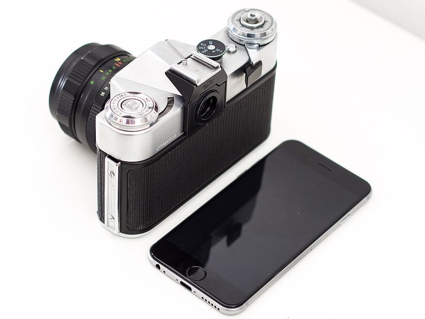 Vintage film camera and modern smartphone on white background