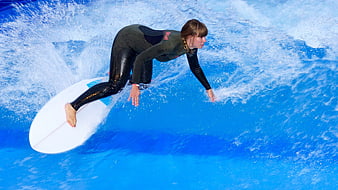 Woman surfing on artificial wave in wetsuit
