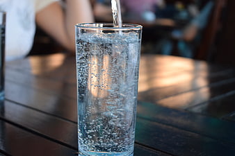 Sparkling water being poured into a glass on a wooden table